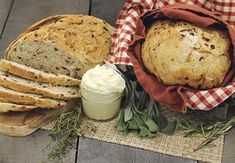 bread, butter and herbs sit on a table next to a napkin with a red checkered cloth