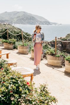 a woman walking down a path next to the ocean