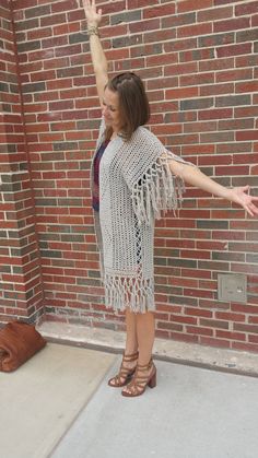 a woman is standing in front of a brick wall with her arms outstretched and legs crossed