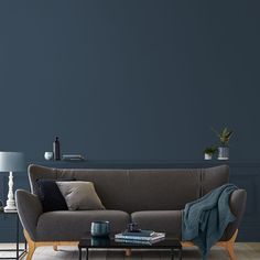 a living room with a couch, table and lamp on the side wall in front of it