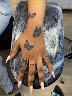 a woman's hand with butterflies on it and hearts tattooed on the middle finger