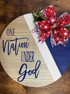 a wooden sign that says, one nation under god with a red white and blue bow