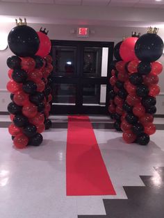 some black and red balloons are on the floor in front of an entrance to a building