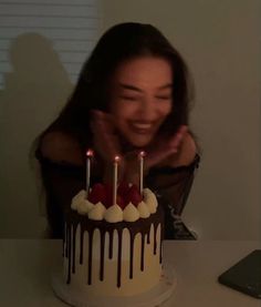 a woman sitting in front of a cake with candles on it