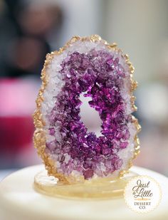 a close up of a purple and white object on a cake with gold trimmings