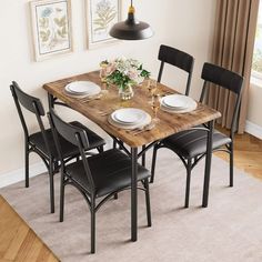 a dining room table with four chairs and plates on the wooden top, in front of a window