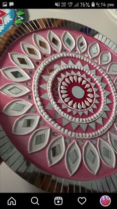 a pink and white circular mirror sitting on top of a table next to a wall