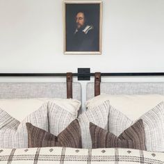 a bed with two pillows on top of it and a painting above the headboard