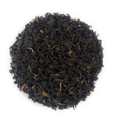 a pile of black tea sitting on top of a white table