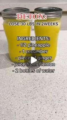 two jars filled with yellow liquid sitting on top of a counter next to each other