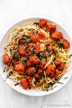 a white bowl filled with spaghetti and tomatoes