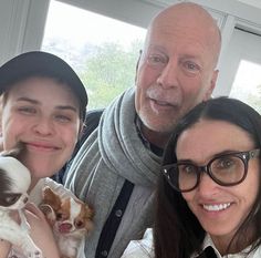 two women and a man holding small dogs