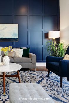 a living room with two couches and a coffee table in front of a blue paneled wall