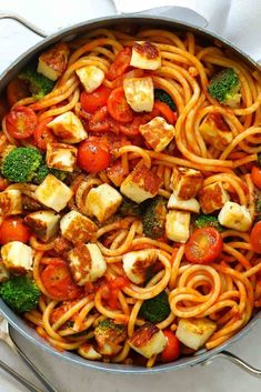 a pan filled with pasta and vegetables on top of a table