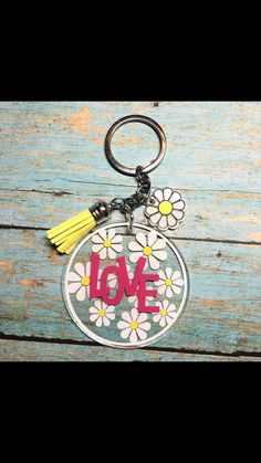 a keychain with the word love written on it and daisies around it