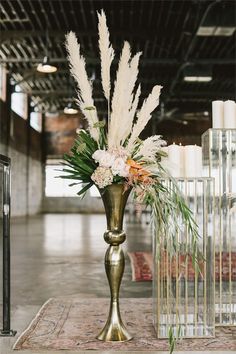 a vase with white flowers and greenery in it on a table next to candles