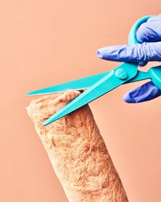 a person in blue gloves holding scissors over a piece of fabric that has been cut