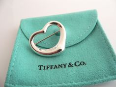 Overview:Offered for sale is a wonderful Tiffany and Co. Silver Peretti Open Heart Brooch/Pin.   The piece is made from substantial Tiffany silver formed into Peretti's classic Open Heart Heart shape.  In very good condition, this piece is one that you will turn to very often to jazz up your wardrobe.  It is no longer produced, and thus makes a great addition for any Tiffany collector.   The piece has a perfectly working locking mechanism, and is fully hallmarked.Everyone needs a Signature Ti Rare Gifts, Heart Pin, Locking Mechanism, Heart Brooch, Gift Love, Tiffany And Co, Open Heart, Matching Necklaces, Blue Bags