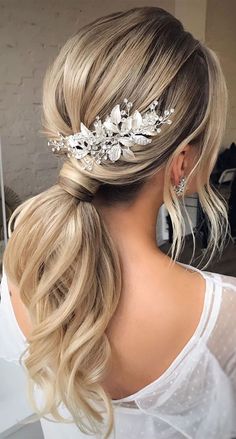 a woman with blonde hair in a ponytail wearing a bridal headpiece made of flowers