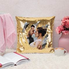 a gold sequin pillow with a photo of a bride and groom on it next to a cup of coffee