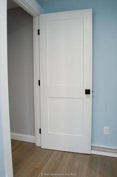 an empty room with a white door and hard wood floor