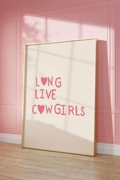 a pink room with a large white framed poster on the wall that says long live cowgirls