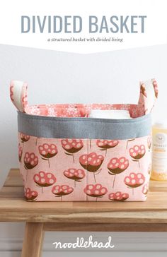 a pink flowered basket sitting on top of a wooden table