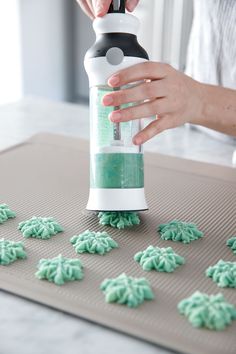 someone is decorating cookies with green icing