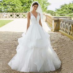 a woman in a wedding dress standing on a bridge