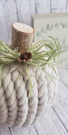 a white rope ball with a pine cone on top sitting next to a wood log