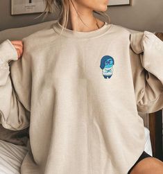 Introducing our Inside Out Character Embroidered Sweatshirt, the perfect addition to any movie lover’s wardrobe. This Cartoon Movie Shirt features vibrant and detailed embroidery of your favorite characters from the beloved film. Made from high-quality materials, it offers exceptional comfort and durability. Whether you’re planning a Family Trip or need a unique Birthday Gift, this sweatshirt is sure to impress. With its eye-catching design and superior craftsmanship, it offers incre Disney Crew Neck Sweatshirt Fan Merchandise, Disney Crew Neck Sweatshirt For Fans, Disney Fan Merchandise Crew Neck Sweatshirt, Disney Embroidered Crew Neck Tops, Disney Cotton Tops With Embroidered Graphics, Disney Style Embroidered Cotton Tops, Disney Embroidered Cotton Tops, Disney Cotton Sweatshirt With Embroidered Graphics, Disney Embroidered Long Sleeve Sweatshirt