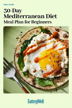 a plate with an egg on top of it next to a fork and spoons