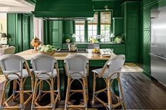 a kitchen with green painted walls and chairs around the island in front of an oven