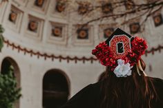 a woman wearing a graduation cap with flowers in her hair is looking up at the ceiling