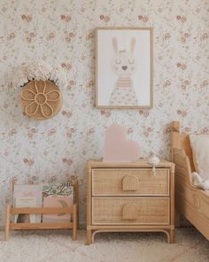 a baby's room with floral wallpaper and a wooden dresser in the foreground