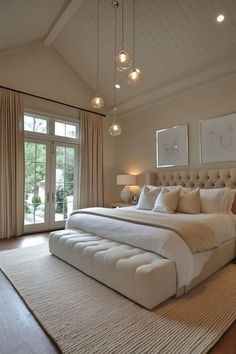 a large white bed sitting inside of a bedroom next to two lamps on either side of the bed