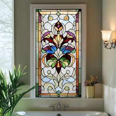 a bath tub sitting under a stained glass window next to a potted green plant