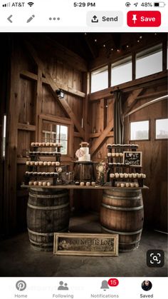 a table topped with lots of wooden barrels filled with cake next to wine glasses and bottles