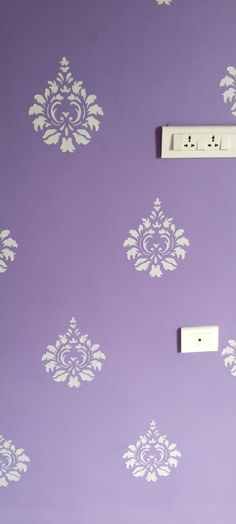 an electrical outlet on a purple wall with white stencils and damask designs