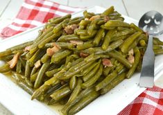 green beans and bacon on a white plate with a red checkered table cloth next to it