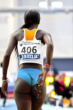 a woman with her back turned to the camera, wearing blue shorts and a white tank top