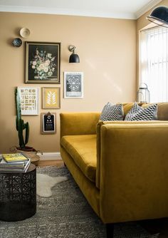 a living room with yellow couches and pictures on the wall above them, along with a coffee table