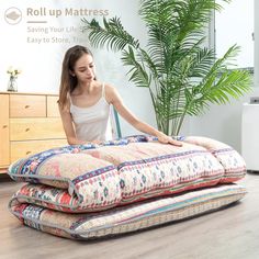 a woman sitting on top of three pillows in the middle of a room with a plant