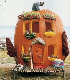 there is a pumpkin shaped house with a statue on top of it and many other things around it