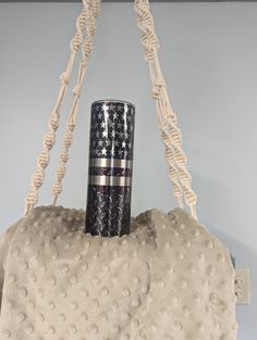 a black and white vase sitting on top of a beige blanket hanging from a hook