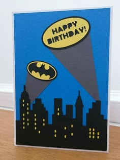 a birthday card with a batman flying through the air over a city skyline at night