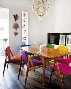 a dining room table with colorful chairs around it