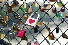 several padlocks attached to a chain link fence with hearts and locks on them