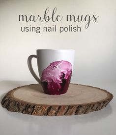 a coffee cup sitting on top of a tree stump with the words marble mugs using nail polish