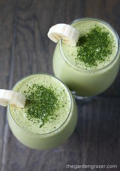 two glasses filled with green smoothie and bananas